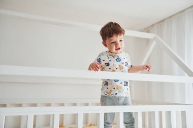 Tatlı küçük çocuk dinleniyor ve yatak odasında eğleniyor..