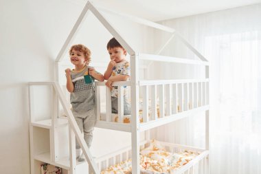 İki küçük çocuk dinleniyor ve yatak odasında birlikte eğleniyorlar..