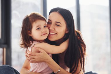 Genç anne ve kızı yatakta birbirlerine sarılıyorlar..