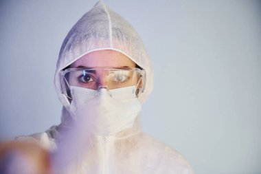 Laboratuvar önlüklü, koruyucu gözlüklü ve maskeli kadın doktor portresi..