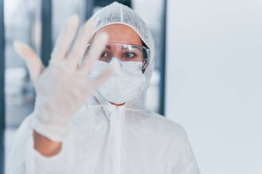 Stop the virus sign. Portrait of female doctor scientist in lab coat, defensive eyewear and mask.