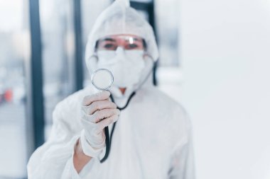 Steteskopla. Laboratuvar önlüklü, koruyucu gözlüklü ve maskeli kadın doktor portresi..