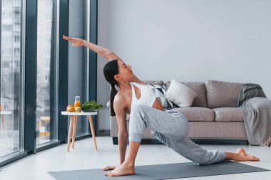 Diyet kavramı. Spor kıyafetleri içinde ince vücutlu genç bir kadın evde spor yapıyor..