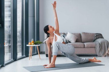 Diyet kavramı. Spor kıyafetleri içinde ince vücutlu genç bir kadın evde spor yapıyor..