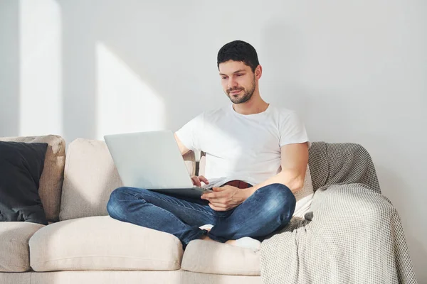 Man White Shirt Jeans Sitting Bed Laptop Indoors — Stok fotoğraf