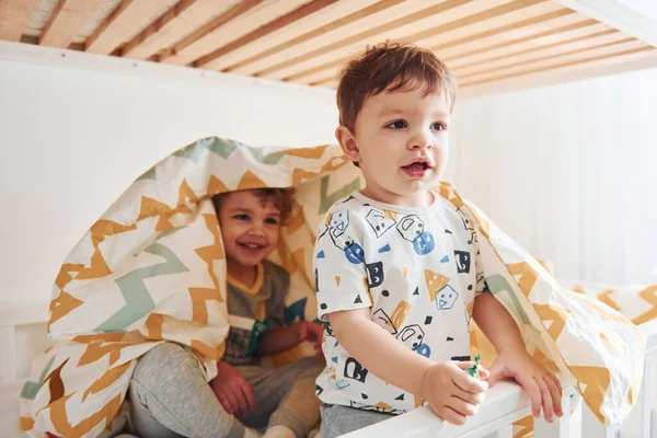 İki küçük çocuk dinleniyor ve yatak odasında birlikte eğleniyorlar..