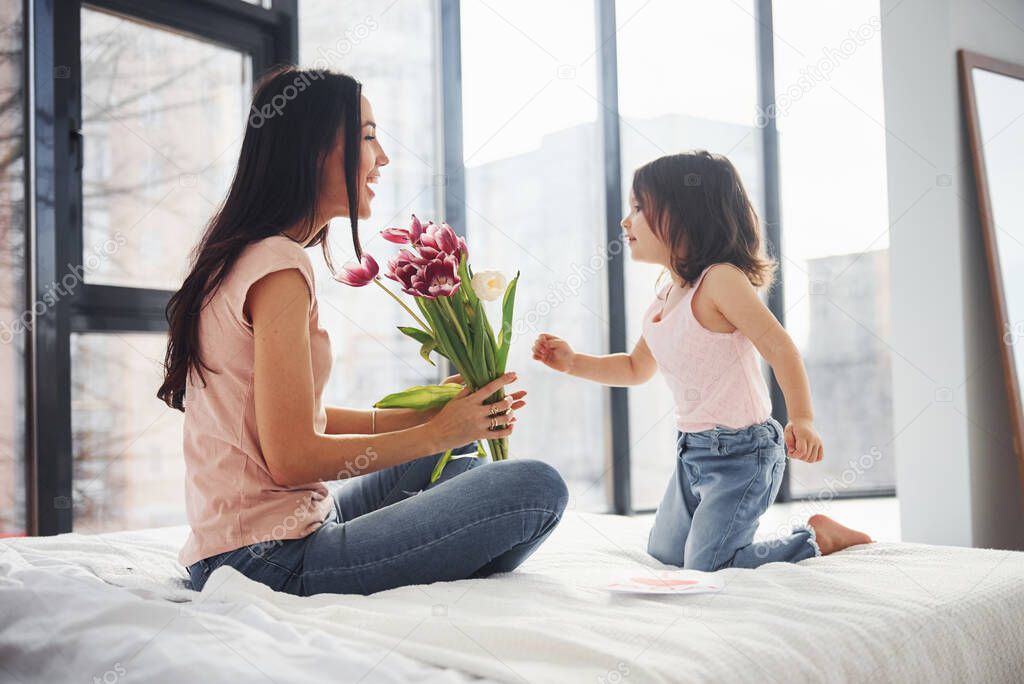 Daughter congratulates mother with holiday and gives bouquet of flowers.