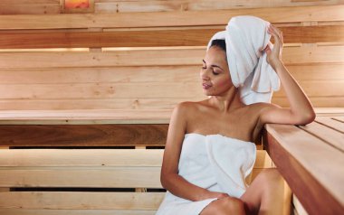 Genç ve güzel bir kadın saunada dinleniyor. Bakım kavramı.
