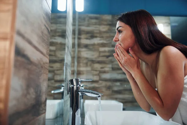 Beautiful Young Woman Standing Bathroom Mirror Washing Her Face — Fotografia de Stock