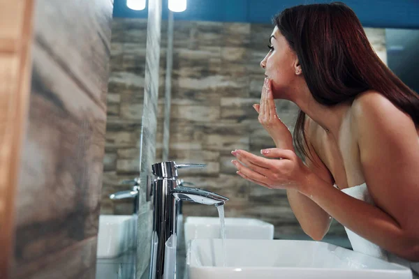 Beautiful Young Woman Standing Bathroom Mirror Washing Her Face — Fotografia de Stock