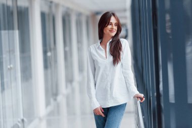 Modern havaalanında ya da gündüz vakti koridorda beyaz gömlekli esmer bir kadın..