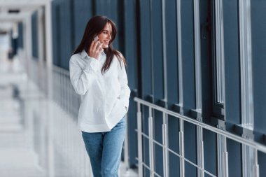 Beyaz gömlekli esmer, modern havaalanında ya da gündüz vakti telefonla konuşan..