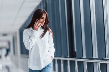 Beyaz gömlekli esmer, modern havaalanında ya da gündüz vakti telefonla konuşan..