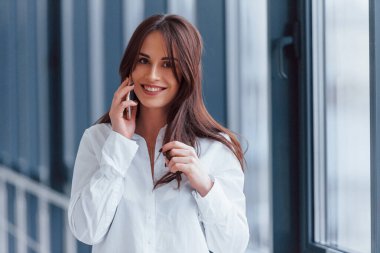 Beyaz gömlekli esmer, modern havaalanında ya da gündüz vakti telefonla konuşan..