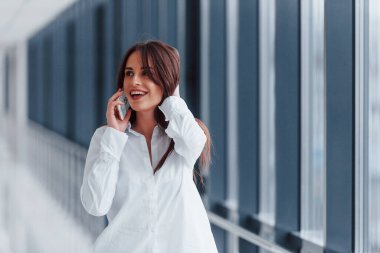 Beyaz gömlekli esmer, modern havaalanında ya da gündüz vakti telefonla konuşan..