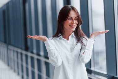 Modern havaalanında ya da gündüz vakti koridorda beyaz gömlekli esmer bir kadın..