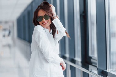 Gündüz vakti modern havaalanında ya da koridorda beyaz gömlekli ve güneş gözlüklü esmer..