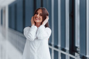 Modern havaalanında ya da gündüz vakti koridorda beyaz gömlekli esmer bir kadın..