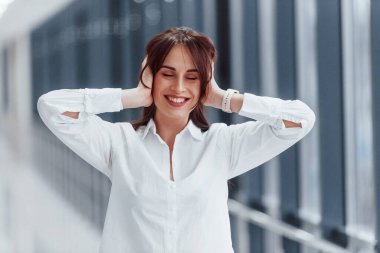 Gündüz vakti modern havaalanında ya da koridorda yürüyen beyaz gömlekli esmer kadın..