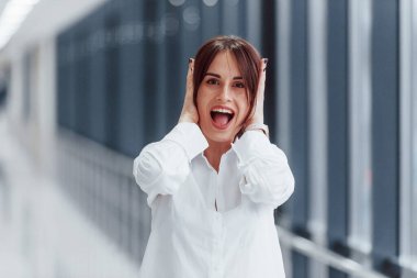 Modern havaalanında ya da gündüz vakti koridorda beyaz gömlekli esmer bir kadın..