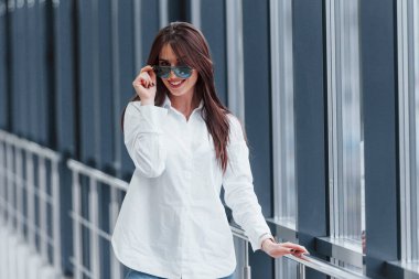 Gündüz vakti modern havaalanında ya da koridorda beyaz gömlekli ve güneş gözlüklü esmer..