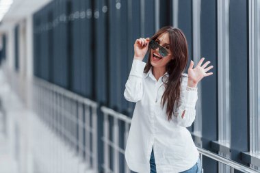 Gündüz vakti modern havaalanında ya da koridorda beyaz gömlekli ve güneş gözlüklü esmer..