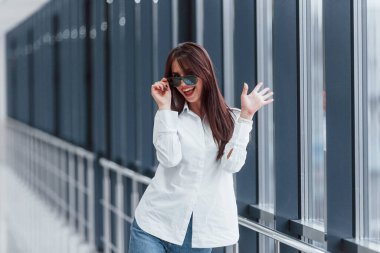 Gündüz vakti modern havaalanında ya da koridorda beyaz gömlekli ve güneş gözlüklü esmer..