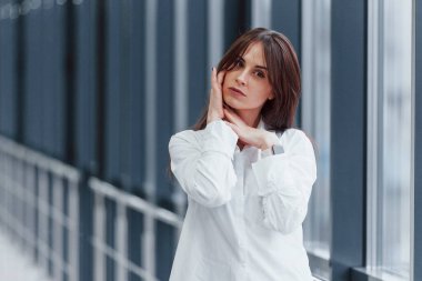 Modern havaalanında ya da gündüz vakti koridorda beyaz gömlekli esmer bir kadın..