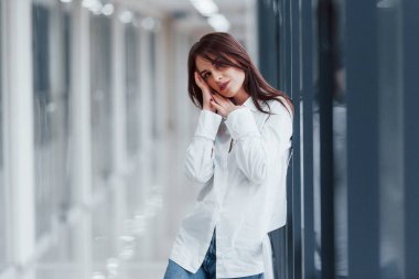 Modern havaalanında ya da gündüz vakti koridorda beyaz gömlekli esmer bir kadın..