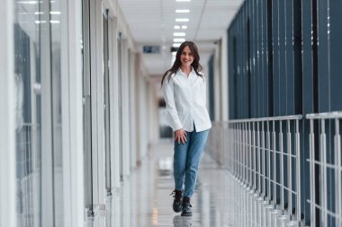 Beyaz gömlekli esmer, modern havaalanında ya da gündüz vakti koridorda yürüyor..