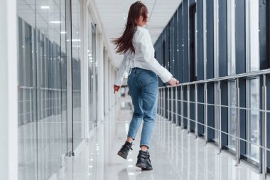 Gündüz vakti modern havaalanında ya da koridorda yürüyen beyaz gömlekli bir kız..