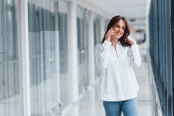 Brunette White Shirt Indoors Talking Phone Modern Airport Hallway Daytime — стоковое фото