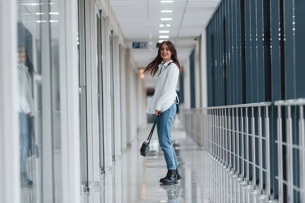 Brunette White Shirt Walks Indoors Modern Airport Hallway Daytime — стоковое фото