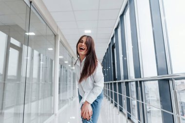 Modern havaalanında ya da gündüz vakti koridorda beyaz gömlekli esmer bir kadın..