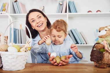 Anne ve kızı birlikte Paskalya bayramını kutluyorlar. Ellerinde yumurta tutarak.