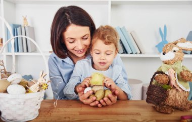 Anne ve kızı birlikte Paskalya bayramını kutluyorlar. Ellerinde yumurta tutarak.