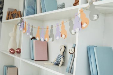 Close up view of shelves with books and Easter toy indoors at home.