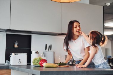 Anne ve küçük kızı mutfakta sebze doğruyor..