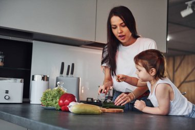 Anne ve küçük kızı mutfakta sebze doğruyor..