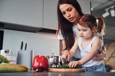 Anne ve küçük kızı mutfakta sebze doğruyor..