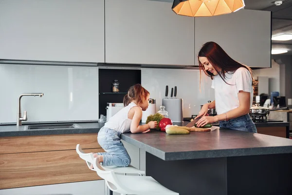 Anne ve küçük kızı mutfakta sebze doğruyor..