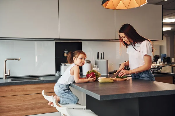 Anne ve küçük kızı mutfakta sebze doğruyor..