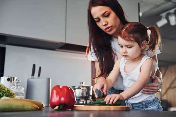 Anne ve küçük kızı mutfakta sebze doğruyor..