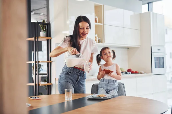 Mother Pouring Fresh Milk Glass Her Little Daughter Kitchen — Stockfoto