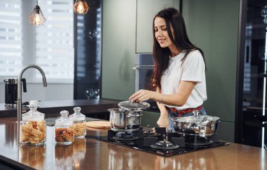 Taze yemek hazırlıyorum. Genç ve güzel esmer, gündüzleri evde, mutfakta günlük giysiler içinde..