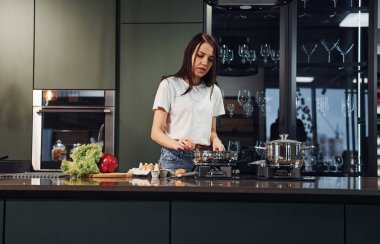 Sebze ve sağlıklı ürünler kullanarak yemek hazırlamak. Genç ve güzel esmer, gündüzleri evde, mutfakta günlük giysiler içinde..