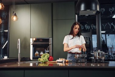 Sebze ve sağlıklı ürünler kullanarak yemek hazırlamak. Genç ve güzel esmer, gündüzleri evde, mutfakta günlük giysiler içinde..