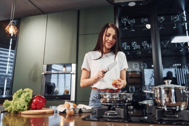 Sebze ve sağlıklı ürünler kullanarak yemek hazırlamak. Genç ve güzel esmer, gündüzleri evde, mutfakta günlük giysiler içinde..