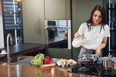 Sebze ve sağlıklı ürünler kullanarak yemek hazırlamak. Genç ve güzel esmer, gündüzleri evde, mutfakta günlük giysiler içinde..
