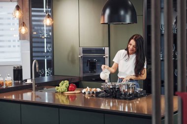 Sebze ve sağlıklı ürünler kullanarak yemek hazırlamak. Genç ve güzel esmer, gündüzleri evde, mutfakta günlük giysiler içinde..